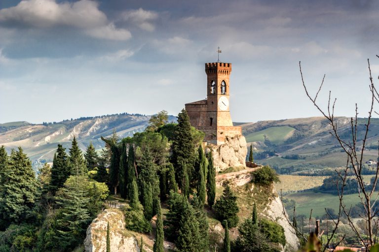 The medieval clock tower surrounded by cypress and other trees, viewed from the Rock of Brisighella in Emilia Romagna, Italy