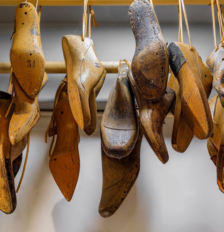 Selection of Italian footwear shoe and boot forms or lasts for custom shoemaking hanging in a leather and shoemaker store in Venice, Italy