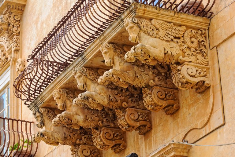 Wrought-iron balcony of the baroque Villadorata Palace in Via Nicolaci supported by five carved winged horses - Noto, Sicily, Italy